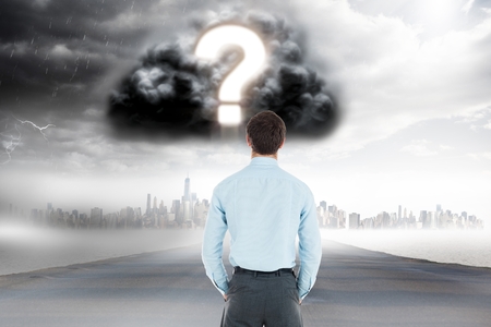 Digital composite of Digitally generated image of businessman looking at question mark in cloudy sky over cityの写真素材