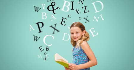 Digital composite of Happy girl holding book while letters flying in backgroundの写真素材