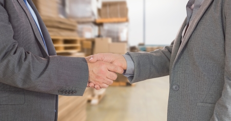 Digital composite of Midsection of businessmen doing handshake in warehouseの写真素材