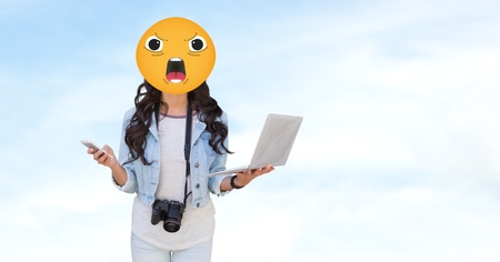 Digital composite of Woman with angry emoji holding laptopの写真素材