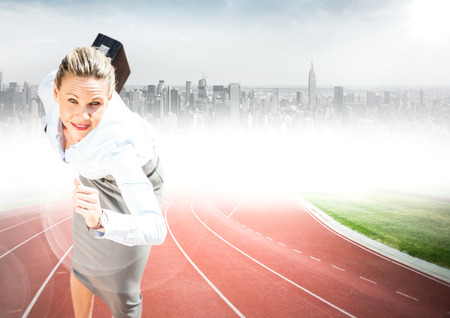 Digital composite of Business woman with briefcase running on track against blurry skyline with flaresの写真素材