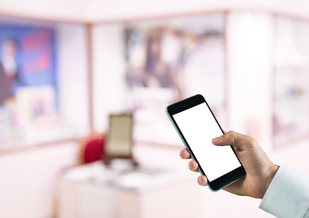 Digital composite of hand with phone in the storeの写真素材