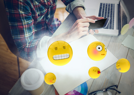 Digital composite of Man at desk with phone and emojis with cloudの写真素材