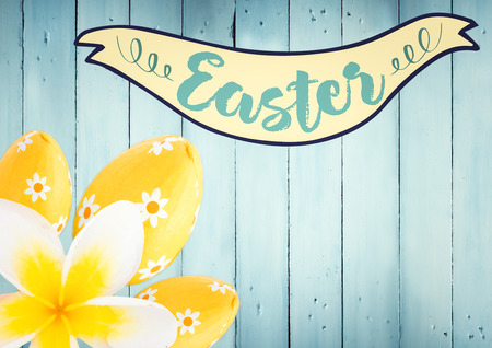 Digital composite of Easter banner with yellow flower and eggs against blue wood panelの写真素材