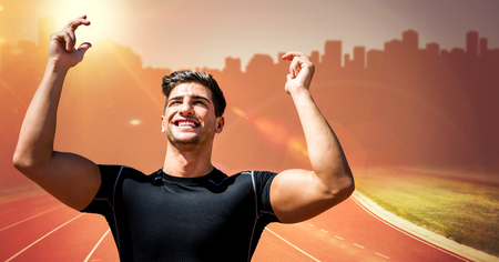 Digital composite of Male runner with hands in air on track against orange flare and blurry skylineの写真素材