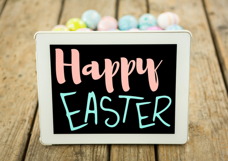 Digital composite of Pink and blue type on tablet on wood table with easter eggsの写真素材