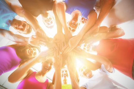 Low angle view of fit people stacking hands at health club