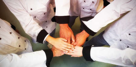 High angle view of chef stacking hands while standing in kitchenの写真素材