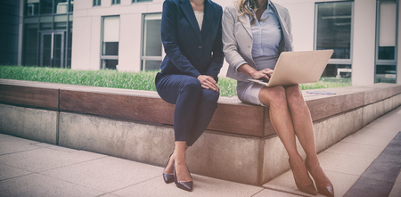 Businesswomen sitting and using laptop in office premisesの写真素材