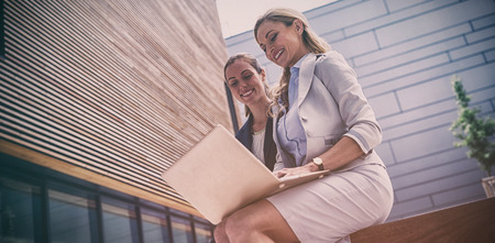 Businesswomen sitting and using laptop in office premisesの写真素材
