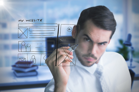 Focused businessman writing with marker against composite image of workplaceの写真素材
