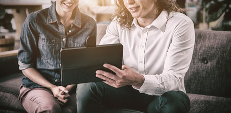 Smiling business colleagues discussing over digital tablet in office