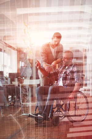 Blue data against businessman showing digital tablet to handicap colleagueの写真素材