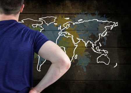 Digital composite of Man in T-Shirt looking at Colorful Map with paint splatters on wall backgroundの写真素材