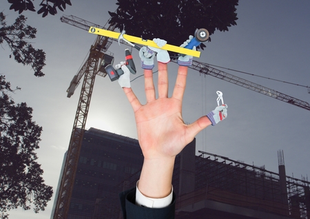 Digital composite of Hand with hands with tools on the fingers in front of the constructionの写真素材