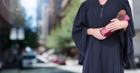 Digital composite of Judge holding book in front of cityの写真素材