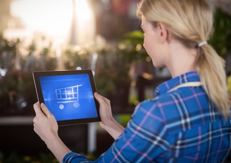 Digital composite of Woman using Tablet with Shopping trolley icon