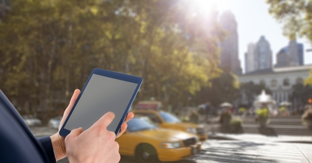Digital composite of Hands with tablet in front of taxis in the city