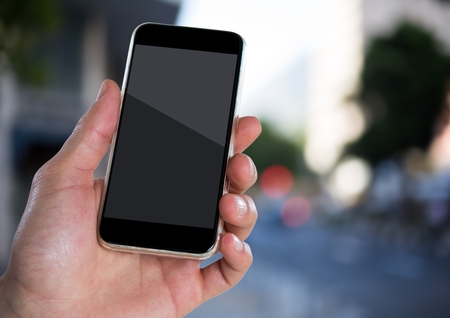 Digital composite of Hand with phone against blurry street