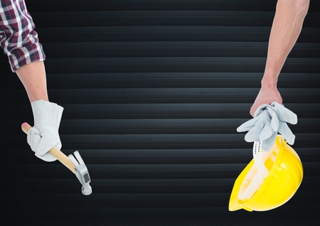 Digital composite of Hand with hammer and hand with tellow hat  in front of blindの写真素材