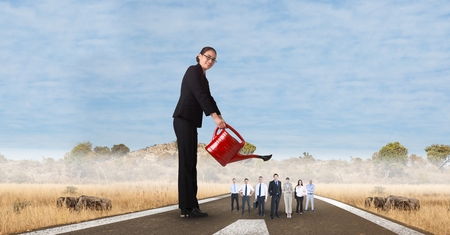 Digital composite of Digital composite image of female manager watering employees on streetの写真素材