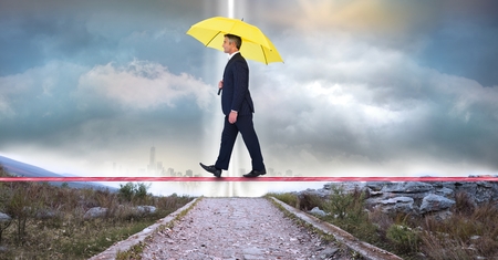 Digital composite of Businessman carrying umbrella while walking on ropeの写真素材