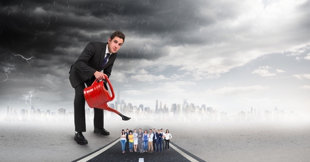 Digital composite of Large businessman pouring water on employees against storm cloudsの写真素材