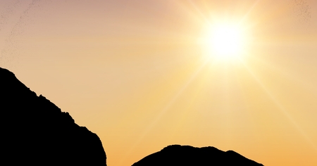 Digital composite of Sun shining over silhouette mountainsの写真素材