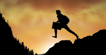 Digital composite of Silhouette businessman jumping on mountain against skyの写真素材