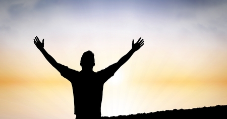 Digital composite of Silhouette man with hands raised against skyの写真素材