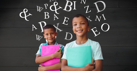 Digital composite of Smiling schoolboys holding books while letters flying in backgroundの写真素材