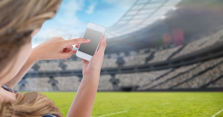 Digital composite of Woman touching blank screen of mobile phone at stadiumの写真素材