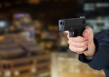 Digital composite of Hand holding gun with night city