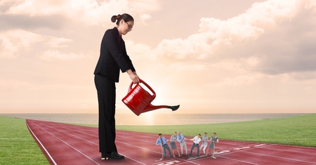Digital composite of Businesswoman watering employees on running tracks against cloudy skyの写真素材
