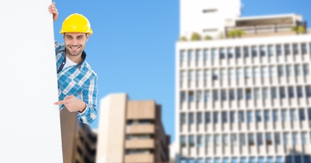 Digital composite of Portrait of smiling male architect pointing at blank billboard against buildingsの写真素材