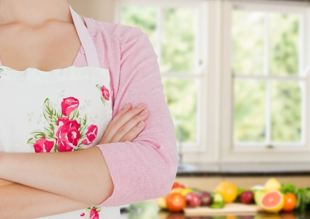 Digital composite of cook woman hand folded in the kitchen. Fruit a vegetables in the backの写真素材