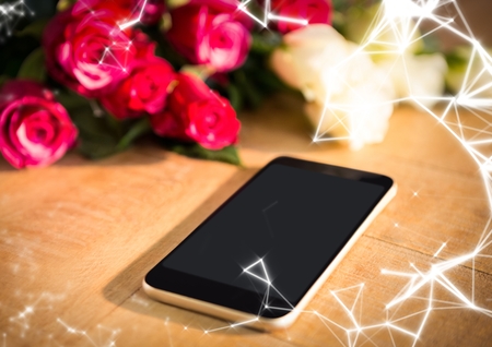 Digital composite of Phone on table with roses and white network overlayの写真素材