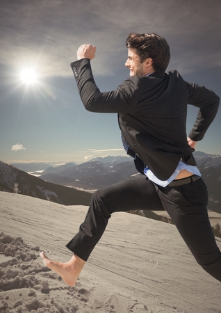 Digital composite of Business man jumping on mountain with sun flareの写真素材