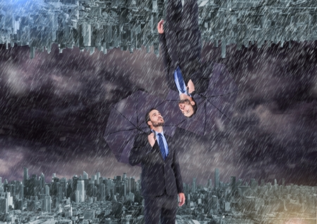 Digital composite of up side down city. raining. Business men with umbrellaの写真素材