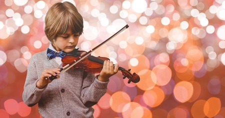 Digital composite of Little boy playing violin over bokehの写真素材