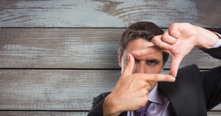 Digital composite of Businessman making finger frame against wooden wallの写真素材