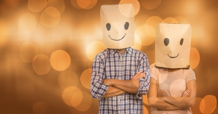Digital composite of Couple covering faces with paper bag with smileys drawn on itの写真素材