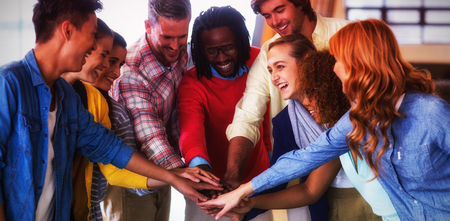 Happy colleagues piling up hands in creative officeの写真素材