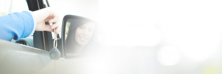 Cheerful teenager girl sitting in car while holding keysの写真素材