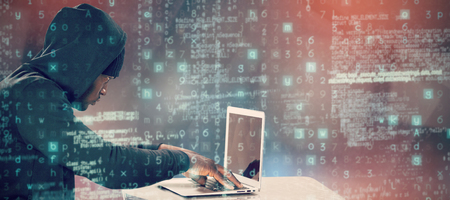 Male hacker using laptop on table  against abstract black room