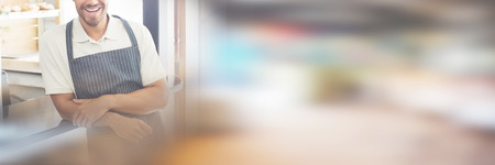 Portrait of smiling confident young waiter standing at cafe counterの写真素材