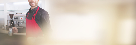 Handsome young barista holding jug and cup at coffee shopの写真素材