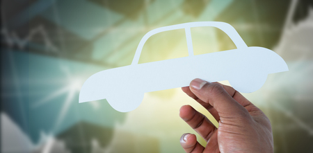 hand holding a car in paper against buildings with graphsの写真素材