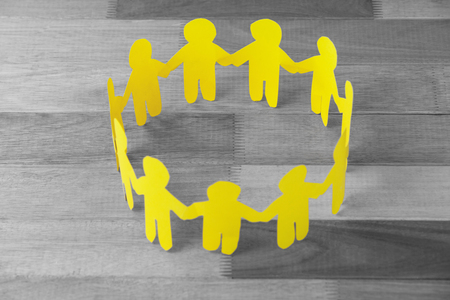 High angle view of yellow paper cut out figures formimg circle on wooden tableの写真素材