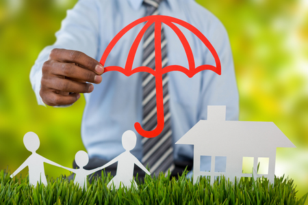 insurer protecting family by a red umbrella against detail shot of bright green leavesの写真素材